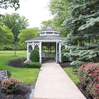 A picturesque gazebo surrounded by lush greenery and a well-maintained garden path.