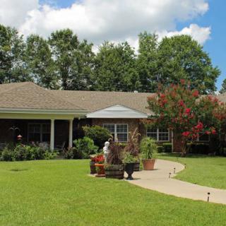 A suburban house with a well-maintained lawn and garden under a partly cloudy sky.