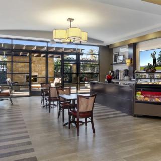 A modern cafe interior with tables, chairs, and a display counter.