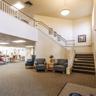 A spacious lobby with a staircase, seating area, and overhead lighting.