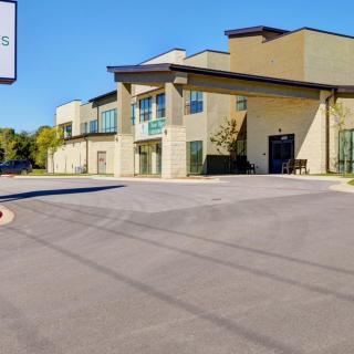 A commercial building with a parking lot and clear blue sky.