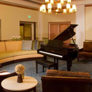 A cozy lounge featuring a grand piano and comfortable seating under a chandelier.