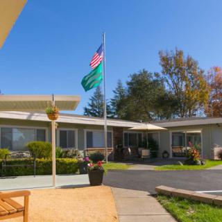 A peaceful courtyard with a building, flagpole, and surrounding greenery under a clear blue sky.
