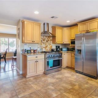 A modern kitchen featuring stainless steel appliances and wooden cabinetry, with an open layout and tile flooring.