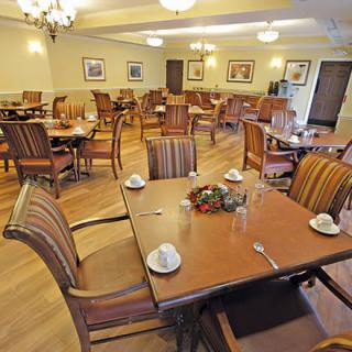An empty dining room with neatly arranged tables and chairs, featuring a warm and inviting interior decor.