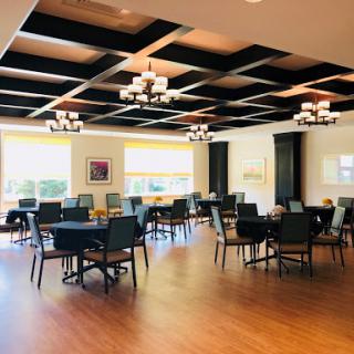 A spacious dining area featuring elegant chandeliers and warm wooden flooring.