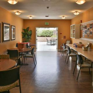 A cozy indoor cafe seating area with tables, chairs, and wall art leading to an outdoor space.