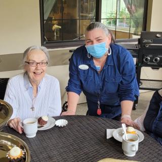 A group of people enjoying coffee and dessert indoors, with one person wearing a mask.