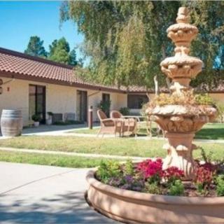 A scenic courtyard with a decorative fountain surrounded by greenery and flowers.