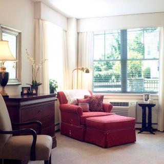 A cozy living room with a red armchair and abundant natural light.