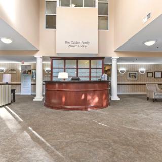 A spacious and well-lit reception area with a central desk and decorative columns.