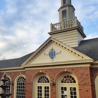 A beautifully designed brick building with a prominent tower, set against a cloudy sky.