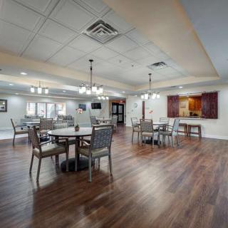 A spacious dining room with modern decor, featuring several tables and chairs, wooden flooring, and elegant lighting fixtures.