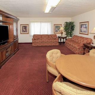 A spacious living room with two sofas, a television, and a round table on a red carpet.