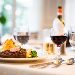 An elegant dining experience featuring a delicious steak, fresh vegetables, and glasses of red wine.