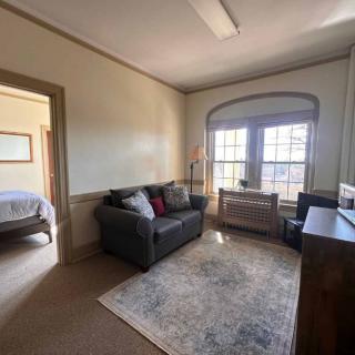 A cozy living room with a sofa, decorative pillows, and ample natural light coming through large windows.