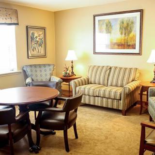A cozy living room with a striped sofa, chairs, table, and artwork on the walls.