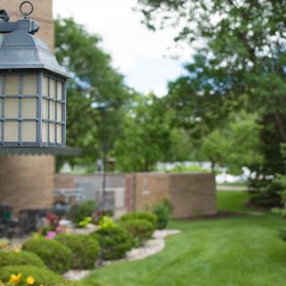 A beautifully landscaped garden with a brick wall and lamp post, surrounded by lush greenery.