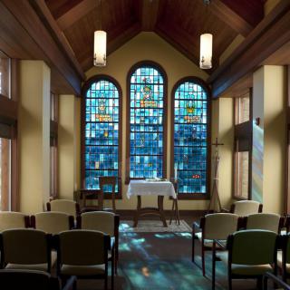 A serene chapel interior with stained glass windows and an altar.