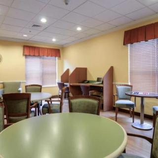 A cozy dining area with several tables and chairs, featuring warm lighting and window blinds.