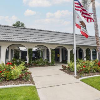 A building with arches surrounded by a garden and featuring flags in front.