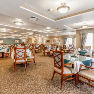An elegant dining room with neatly arranged tables and chairs, featuring warm lighting and classic decor.