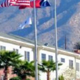 Flags flying in front of a building with mountains in the background.