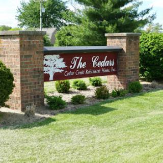 Entrance sign for The Cedars community, surrounded by well-maintained landscaping.