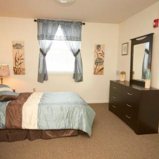 A cozy bedroom with a bed, dresser, and decorative elements.