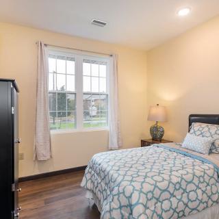 A cozy bedroom with a single bed, soft lighting, and a large window.