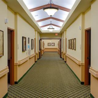 A well-lit hallway featuring framed artwork and patterned carpet.