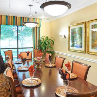 A well-decorated dining room with a large wooden table, cushioned chairs, and elegant light fixtures.