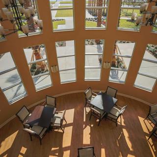 Cozy seating area with tables and chairs bathed in natural sunlight streaming through large windows.