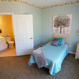 A cozy bedroom with a single bed and blue bedding, featuring an adjacent bathroom.
