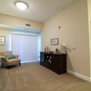 A modern living room interior with a chair, cabinet, and soft lighting.