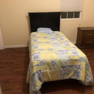 A simple bedroom with a single bed and nightstand.