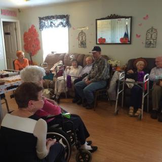 A group of elderly individuals gathered in a community center, enjoying each other's company in a cozy indoor setting.