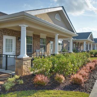 A row of houses with porches and well-maintained gardens.