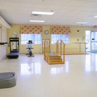 An empty rehabilitation center room equipped with exercise equipment and parallel bars for physical therapy.