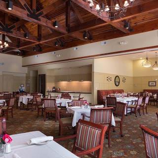 An elegant dining area featuring neatly arranged tables and chairs under beautiful chandeliers.
