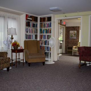 A cozy living room with armchairs and a fully stocked bookshelf.