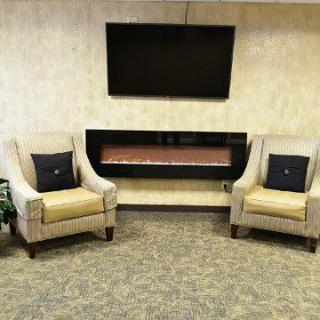 A cozy living room setup with two armchairs facing a wall-mounted television above a modern fireplace.