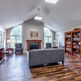 A cozy living room with a fireplace, bookshelves, and large windows.