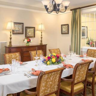 A elegantly set dining room table with floral centerpiece and warm decor.