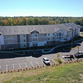 Aerial view of a residential building with a parking lot and surrounding greenery.