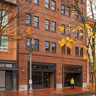 A brick building on a city street with autumnal trees.