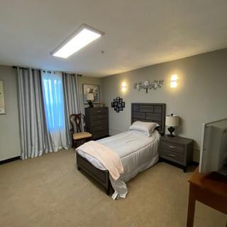 A cozy bedroom with a single bed, dresser, and neutral color scheme.