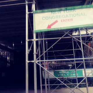 Construction site entrance with scaffolding and directional signage.