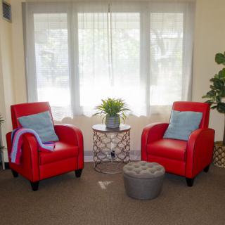 Cozy living room corner with two red armchairs and a side table, illuminated by natural light from the window.