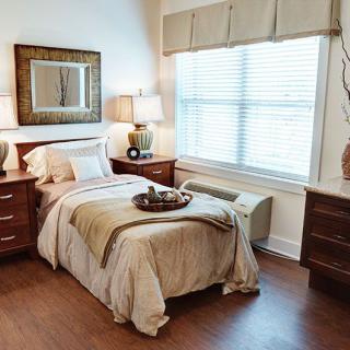 A cozy and well-decorated bedroom with a neatly made bed, two nightstands, and a large window.